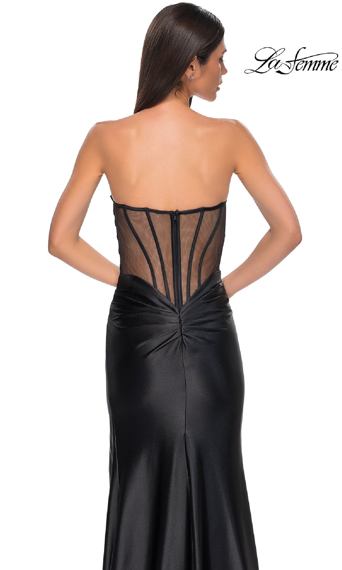 A woman models the Sheer-Back Strapless Prom Gown: La Femme 32649, featuring a sweetheart neckline, ruched satin fabric, and a sheer corset-style back, set against a white background.